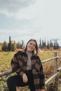 Portrait of smiling young woman sitting on field