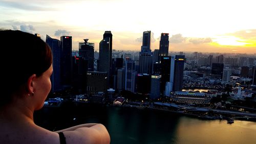 Man looking at city buildings against sky during sunset