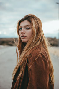 Portrait of young woman standing against sky