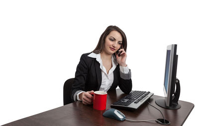 Young woman using phone while sitting on table