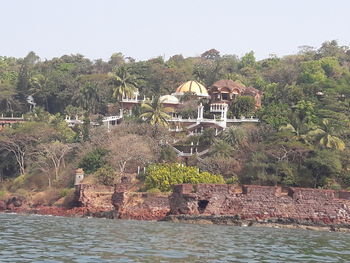 House by river and buildings against sky