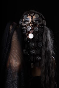 Portrait of woman wearing mask against black background