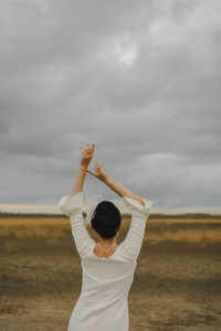 Rear view of woman standing on field against sky