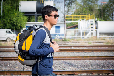 Side view of young man standing on railroad track