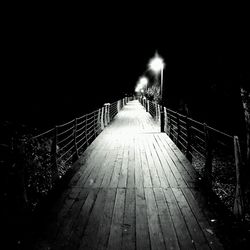 Illuminated footbridge over street at night