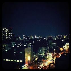 Illuminated cityscape against sky at night