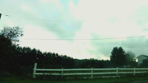 Trees on field against cloudy sky