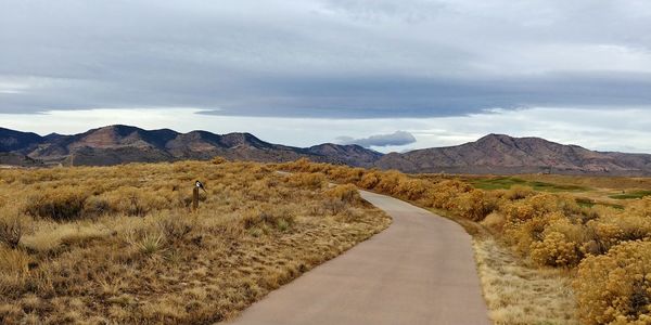 Road leading towards mountains against sky