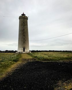 Lighthouse on field against sky