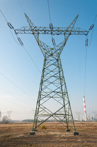 Low angle view of electricity pylon on field against sky