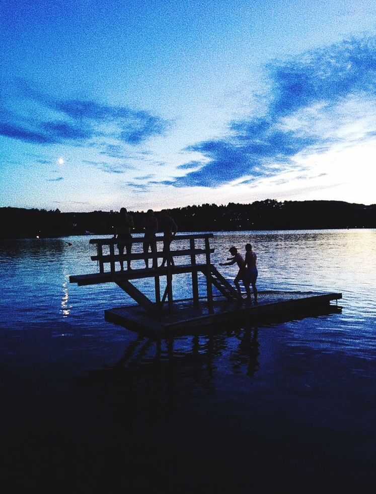 SILHOUETTE PEOPLE IN LAKE AGAINST BLUE SKY