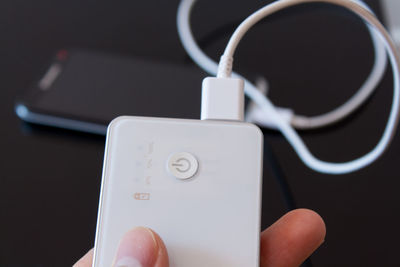 Cropped hand holding portable charger against black background