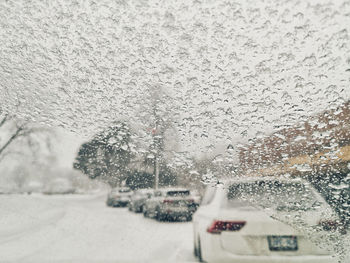 Snow covered city seen through wet car windshield
