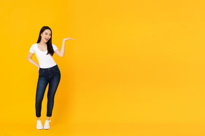 Portrait of a smiling young woman against yellow background