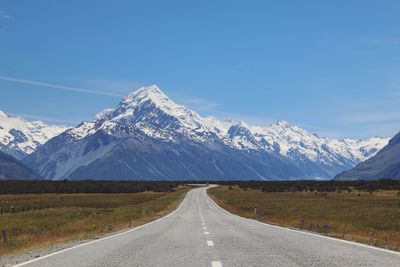 Scenic view of road against snowcapped mountains