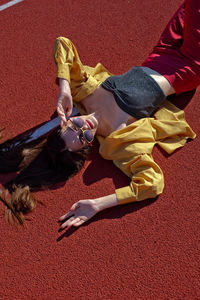 High angle portrait of woman wearing eyeglasses lying on running track