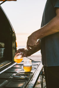 Midsection of man pouring beer in glass