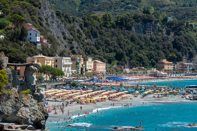 Monterosso, italy, july 27, 2023. beach and parasols in front of the giant, statue god poseidon 