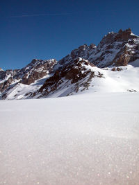 Scenic view of snowcapped mountains against clear blue sky