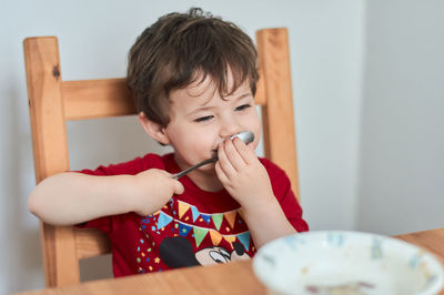 A boy is having fun at the breakfast table eating oatmeal