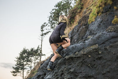 Low angle view of woman standing on rock against clear sky