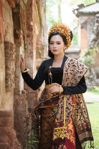 Portrait of young woman standing against wall