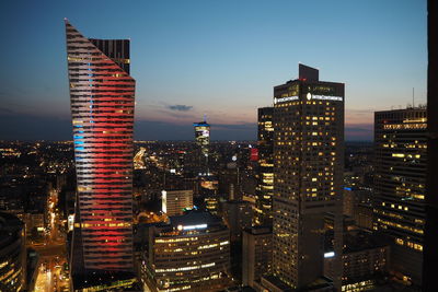 Illuminated buildings in city against sky at night