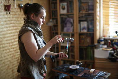 The master woman near the bench works with tools, on the torch boils water with a metal plate. 