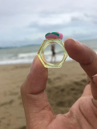 Cropped hand holding crystal ball at beach