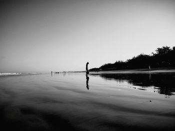 Man standing on beach against clear sky