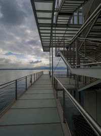 Built structure by sea against cloudy sky during sunset