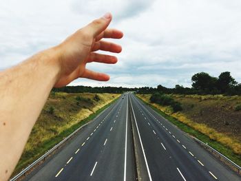 Cropped hand above two lane highway