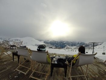 Rear view of male friends relaxing on deck chairs at alpe d huez