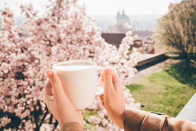 Woman drinking coffee at outdoor cafe with amazing view. close up hands with cup of coffee.