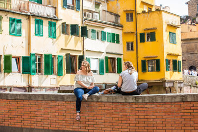 Full length of young woman sitting outside building