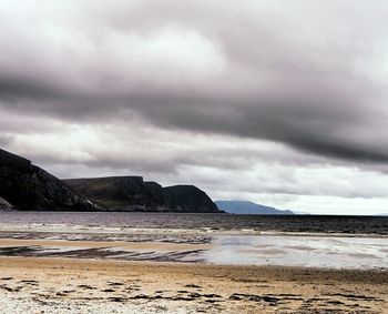 Scenic view of beach against storm clouds