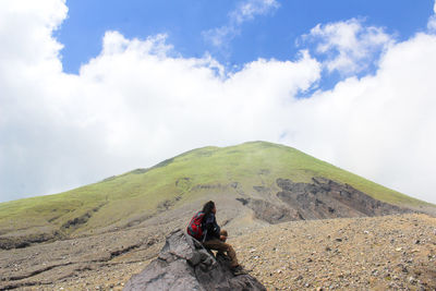 People sitting on mountain against sky
