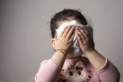 Portrait of woman covering face against wall