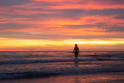 Silhouette person on beach against sky during sunset