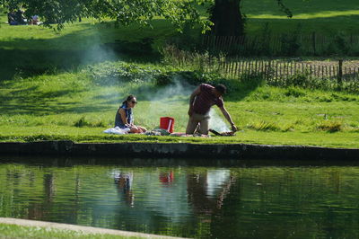 Rear view of people sitting by lake