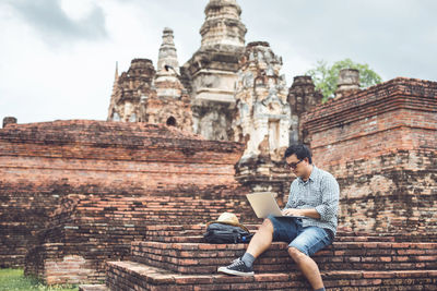 Asian tourist working and using laptop at sukhothai historical park, thailand