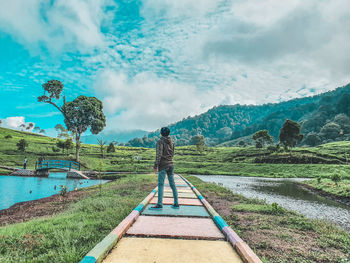 Rear view of person standing on landscape against sky