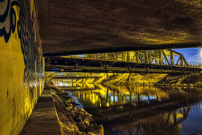 Illuminated bridge over river at night