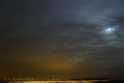 View of illuminated cityscape against cloudy sky