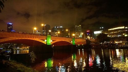 Illuminated bridge over river at night