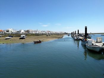 Boats moored in marina against blue sky