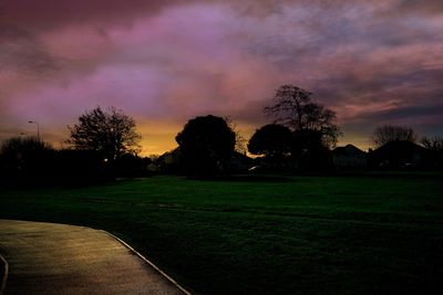 Silhouette trees on field against sky during sunset