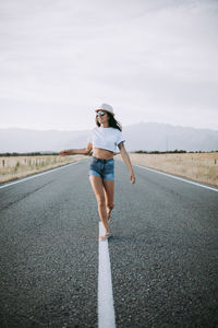 Full length of woman standing on road against sky