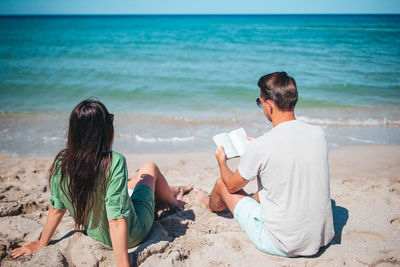 Side view of woman sitting at beach