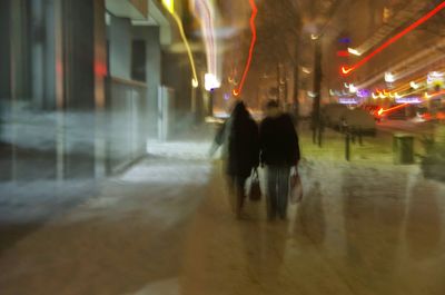 Blurred motion of people walking on road at night